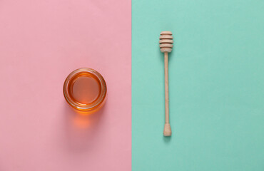 Jar of honey with spoon on pink blue pastel background. Top view. Flat lay