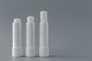 Side view of white lip balm tubes on gray background.