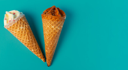 View from above of two cone ice cream with caramel and white chocolate on green background.