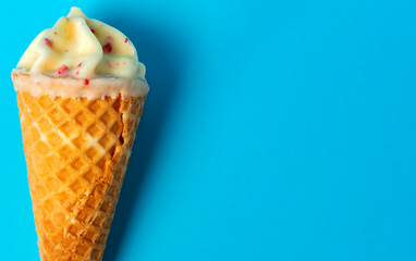 View from above of ice cream with white chocolate and berries on light blue background.