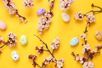 Easter composition. Easter colored eggs on yellow background with beautiful flowering branches