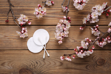 Hygienic cotton pads and ear sticks on wooden background with flowering branches. Hygiene concept