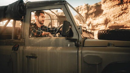 Desert Road Trip: Portrait of Handsome Male Explorer Looking out of Car Driver Window and Smiling....