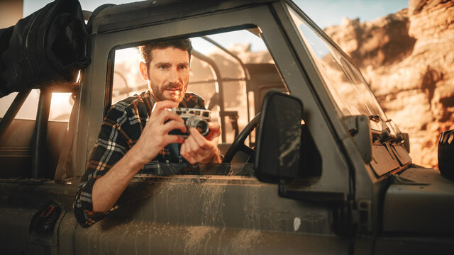 Desert Road Trip: Portrait of Professional Travel Photographer Using Camera, Taking Photos through Side Window of a Car. Offroad SUV Journey through the Rocky Canyon. Documenting Amazing Nature