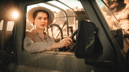 Obraz na płótnie Canvas Desert Road Trip: Portrait of Beautiful Female Explorer Looking out of Car Driver Window and Smiling. Woman Adventurer Traveling through the Canyon on Her Offroad SUV. Journey Through Marvelous Nature