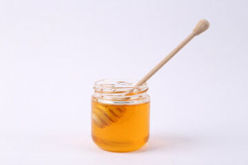 Bee honey jar and honey wooden spoon on white background