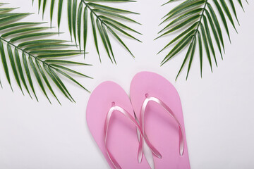 Flip-flops and palm green leaves on white background. Travel concept. Tropical composition. Top view. Flat lay