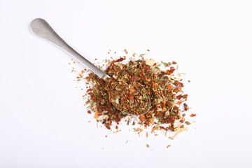 Spice mix, natural chopped seasoning for cooking with spoon isolated on white background