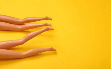 Dolls female bare feet on a blue-pink pastel background. Sunbathe on the beach. Creative minimalistic layout