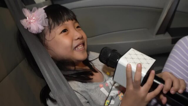 Chinese Kid Girl Happily Sing Song With Bluetooth Mic At Car