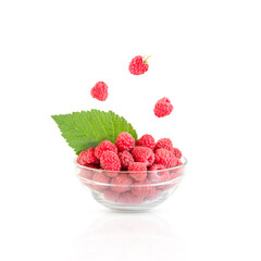 pile of raspberries in a transparent cup and levitating berries isolated on white background
