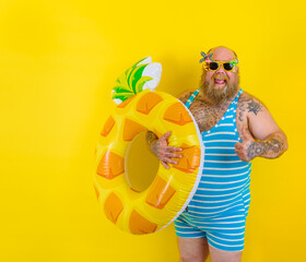 Fat happy man with wig in head is ready to swim with a donut lifesaver