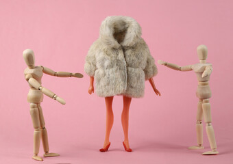 Wooden puppets look at a mannequin in a fashionable fur coat