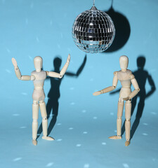Two puppets dancing under disco ball on blue bright background. Minimalism party concept