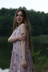 Long haired woman in pink dress standing near water