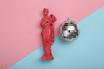 Disco ball and antique sculpture on pink blue background. Minimalism party concept. Top view