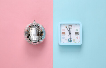 Alarm clock with Disco ball on blue pink background. Minimalism party concept