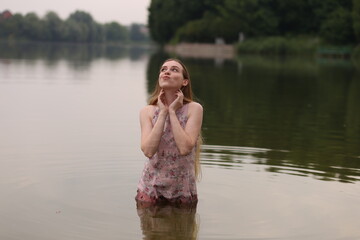 Young woman in pink dress in water of the lake