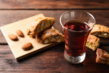 Tasty cantucci and glass of liqueur on wooden table, space for text. Traditional Italian almond biscuits
