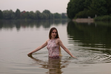 Young woman in pink dress in water of the lake