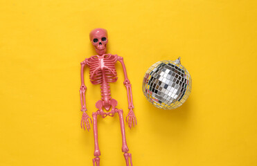 Disco ball and skeleton on yellow background. Minimalism party concept