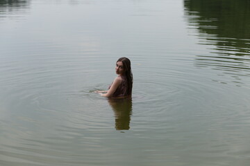 Long haired woman in pink dress swimming in the lake