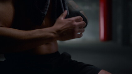Fototapeta premium Kickboxer using boxing tapes for training. Man getting ready for fight 
