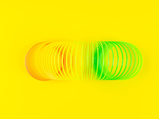 Colorful rainbow spiral plastic toy on yellow background