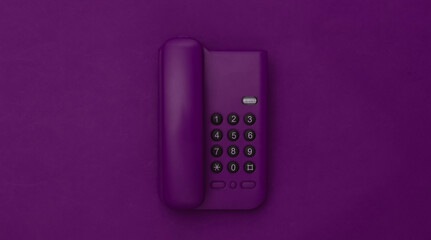 Landline phone on purple background. Top view