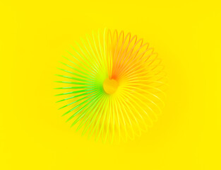 Colorful rainbow spiral plastic toy on yellow background
