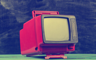 Red retro old school portable mini tv set on blackboard background