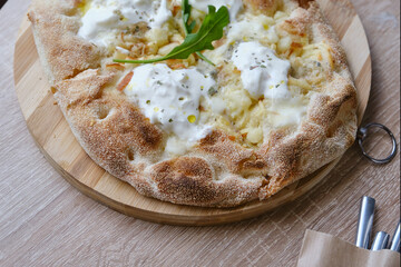 Roman round pizza five or four cheeses on a round wooden kitchen pizza board. Delicious fresh Italian pizza on a round wooden table. Selective focus