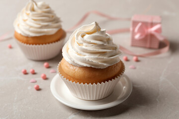 Delicious cupcakes decorated with cream on light grey table