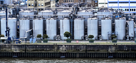 Storage tanks for oil and gasoline at the edge of a harbor basin on a river