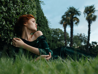 Naklejka na ściany i meble woman in green dress lies on the grass Fairy garden nature
