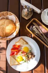 Summer breakfast in a restaurant. Fried eggs with mushrooms and tomatoes