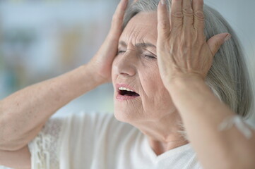 Portrait of sad senior woman with headache