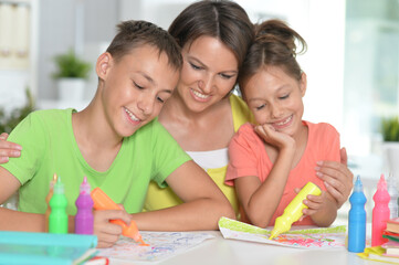 Smiling mother,  brother and sister drawing together