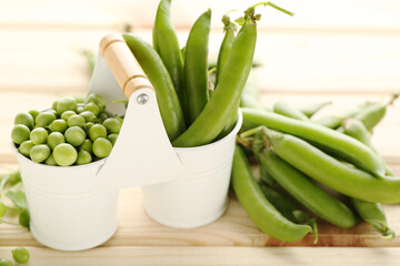 Fresh peas in buckets on brown wooden table
