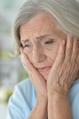 Portrait of sad senior woman with headache