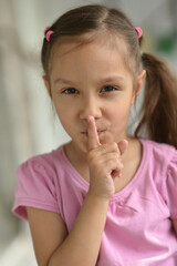 Fototapeta premium cute little girl with silence gesture at home