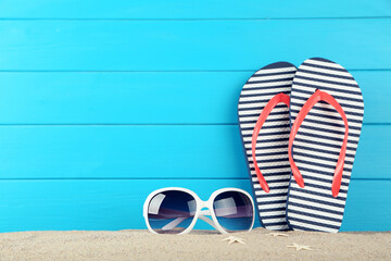 Striped flip-flops with sunglasses and starfishes on blue background