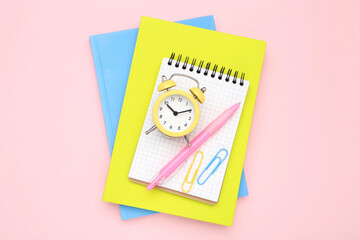 School supplies with alarm clock on pink background