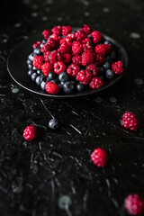raspberries and blueberries, on a black background, wild berry