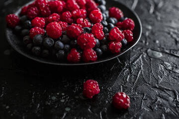 raspberries and blueberries, on a black background, wild berry