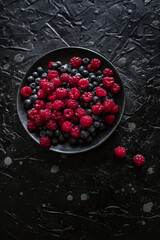 raspberries and blueberries, on a black background, wild berry