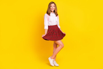 Full size photo of pretty little girl wear shirt skirt bag sneakers isolated on yellow background
