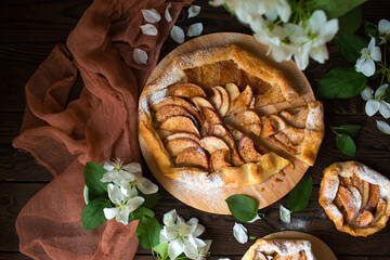 Baked sweet apple pie with honey and cinnamon on a wooden table. Spring biscuits and a blooming apple tree