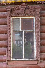The window of an old wooden Russian house with beautiful decorative wood trims.