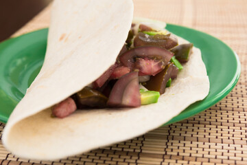 salad of black tomatoes, avocado and onions in Italian tortilla on green plate